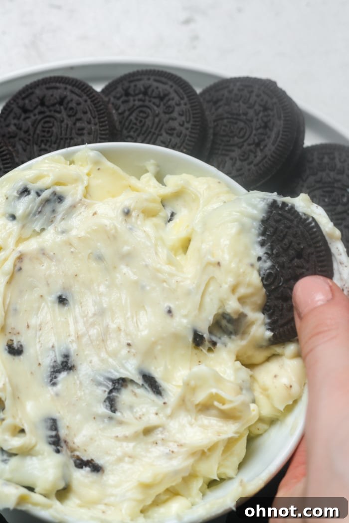 A spoonful of creamy Oreo dip with a whole Oreo cookie on the side, ready to be enjoyed.