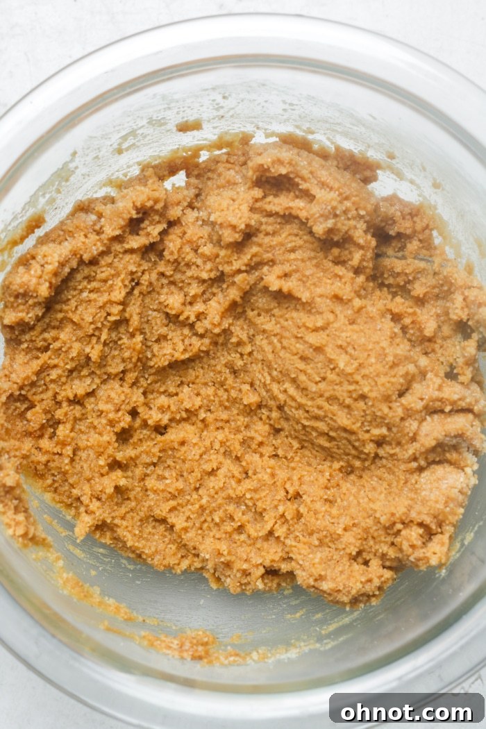 A mixing bowl filled with thick peanut butter cookie dough, ready for shaping.