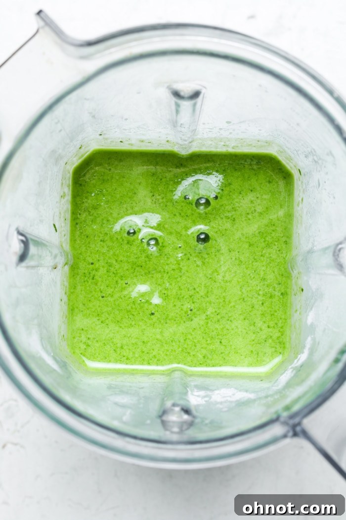 A vibrant, creamy mint green smoothie swirling in a blender, perfectly blended.