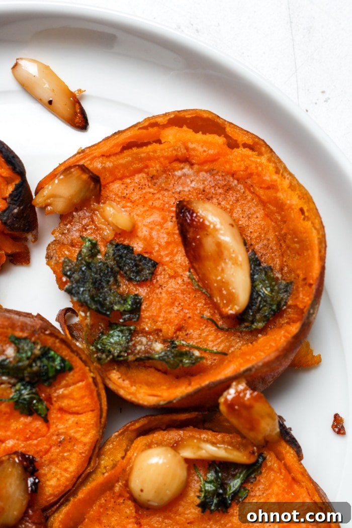 Smashed sweet potatoes garnished with roasted garlic and fresh herbs.