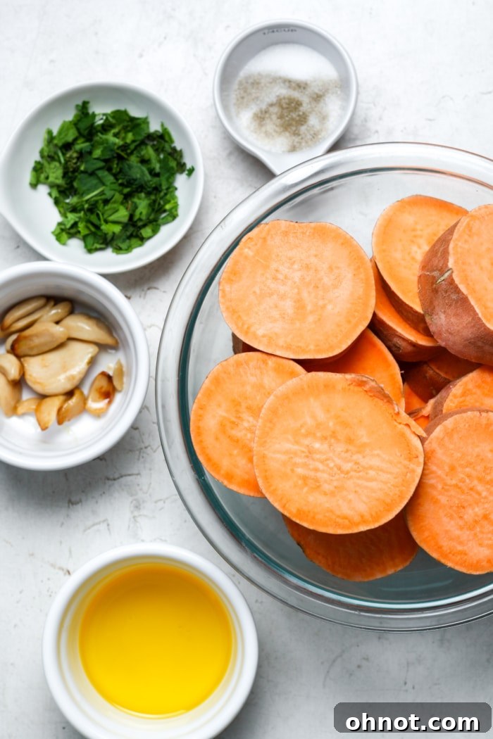 Fresh ingredients for making smashed sweet potatoes, including whole sweet potatoes, herbs, and butter.