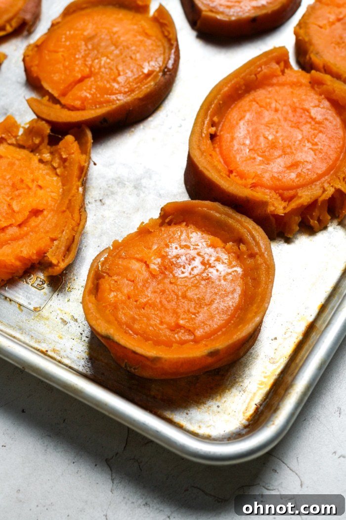 Smashed sweet potato rounds on a baking sheet, ready for seasoning.