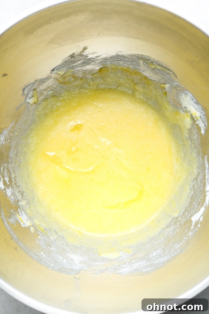 Bright yellow brownie batter, freshly mixed with lemon juice and zest, showcasing its vibrant color.