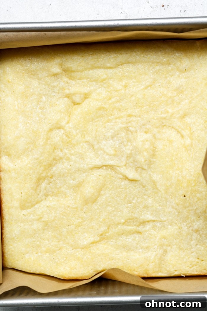 Freshly baked lemon bars, golden brown and puffed, cooling in their square pan.