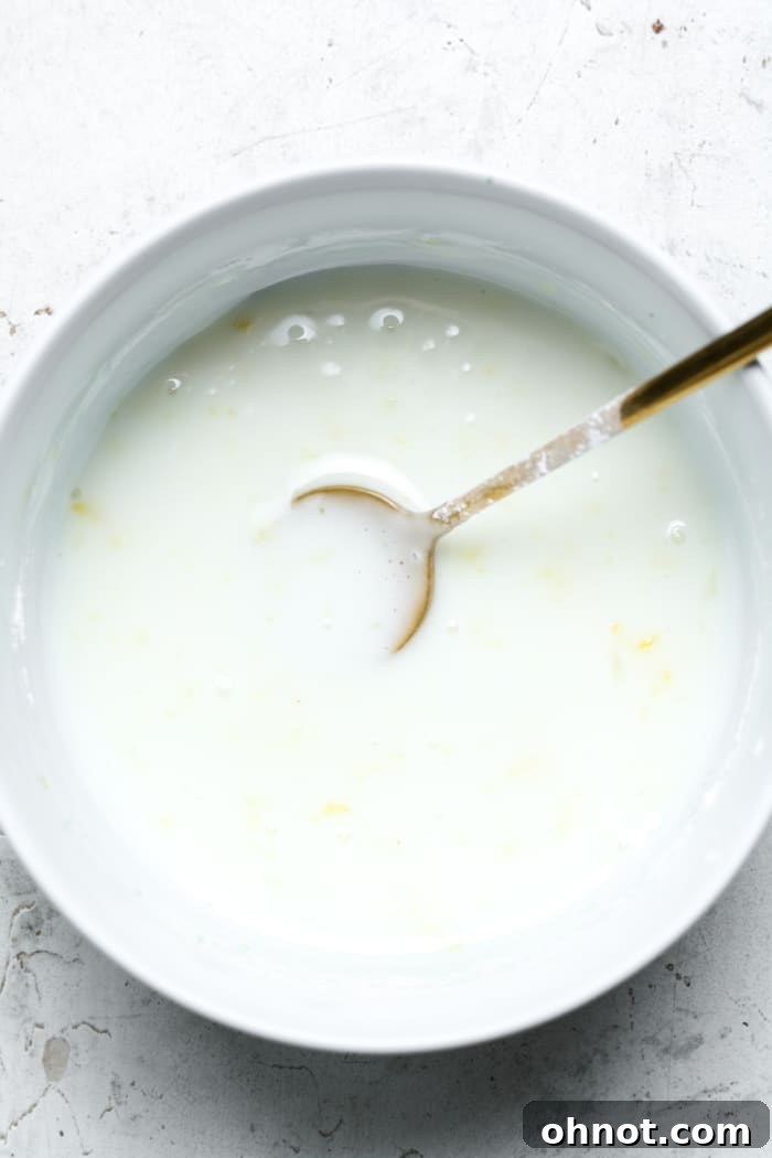 Creamy lemon glaze glistening in a small mixing bowl, ready to be poured.