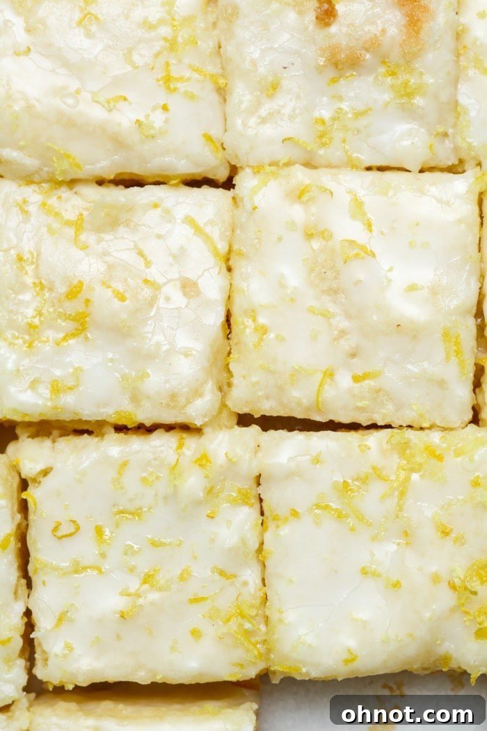 Glazed yellow lemon bars, neatly sliced and arranged, topped with a beautiful lemon frosting.