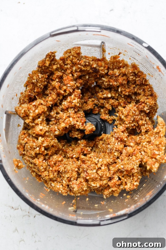 A sticky, vibrant orange mixture in a food processor, representing the blended crust.