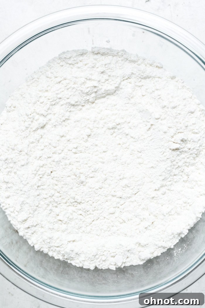 Gluten-free flour, sugar, and baking powder in a glass bowl.