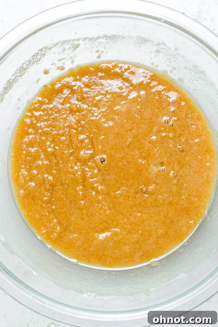Golden batter in a mixing bowl with dry ingredients, being gently mixed.