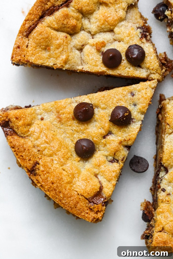 A chocolate chip cookie pie, freshly baked and cooled, sliced into several generous wedges, revealing the thick, gooey chocolate hazelnut filling.