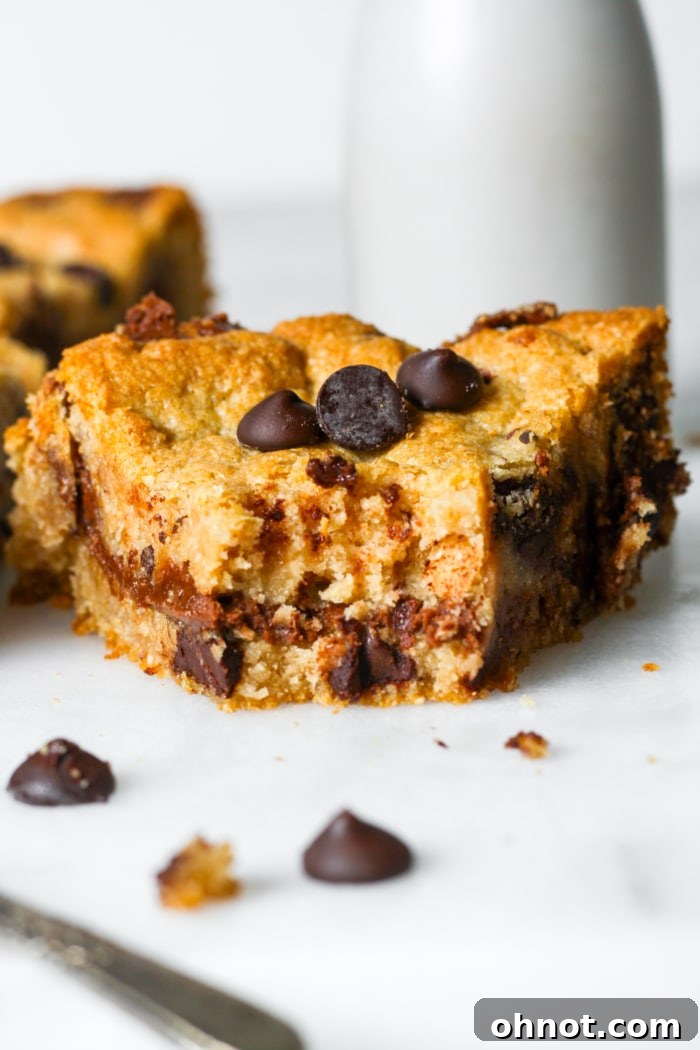 A close-up of a slice of warm chocolate chip cookie pie with a fork, showing the rich, gooey chocolate hazelnut filling and melted chocolate chips.