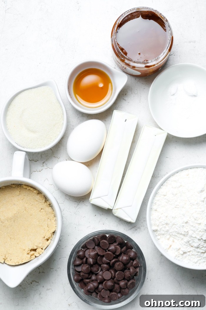Various cookie pie ingredients laid out: butter sticks, bags of sugar, eggs, chocolate chips, and a jar of chocolate hazelnut spread.
