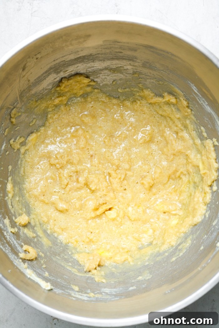 A buttery sugar mixture in a bowl, with eggs and vanilla extract recently added, being stirred to combine.