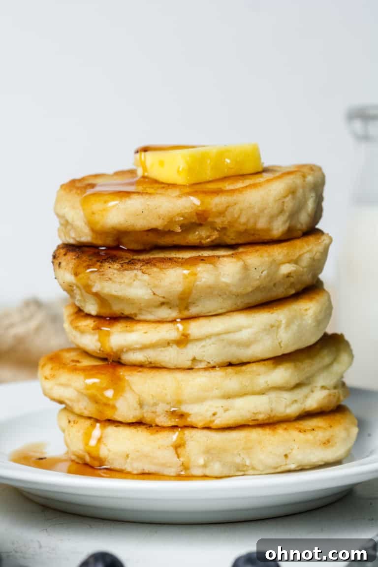 Stack of fluffy gluten-free pancakes with berries and syrup