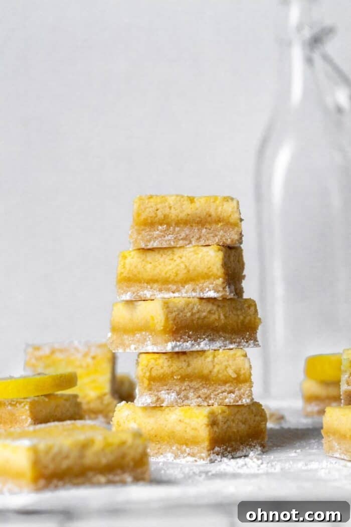 Close-up shot of Paleo Lemon Bars arranged on a marble countertop, highlighting the soft texture of the crust and the vibrant yellow filling.