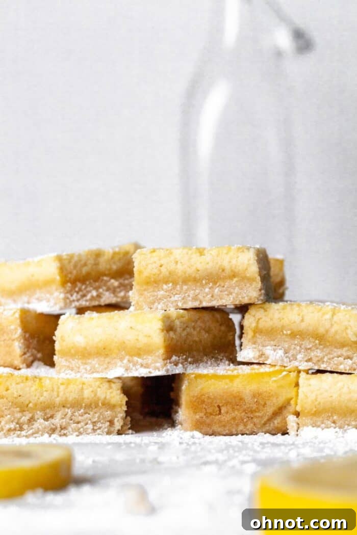A stack of perfectly cut Paleo Lemon Bars on parchment paper, ready to serve and share.