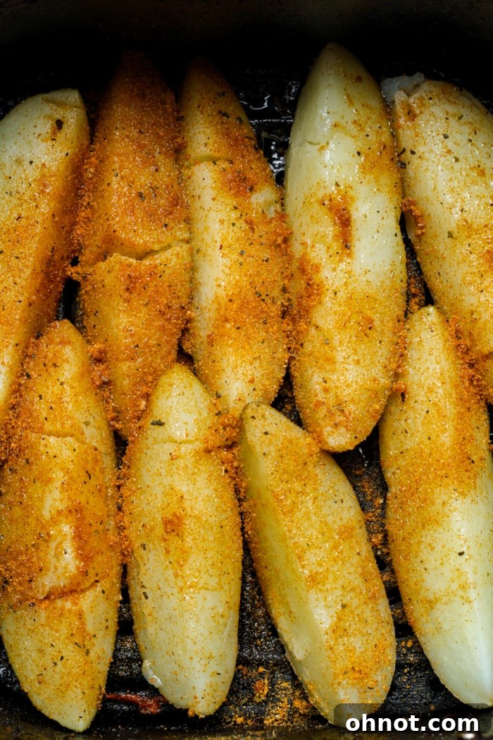 Air fryer basket filled with cooking potato wedges, perfectly spaced.