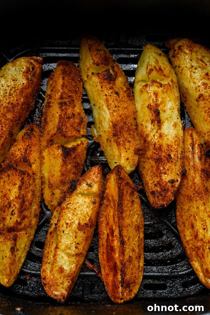 Golden crispy air fried potato wedges emerging from the air fryer.