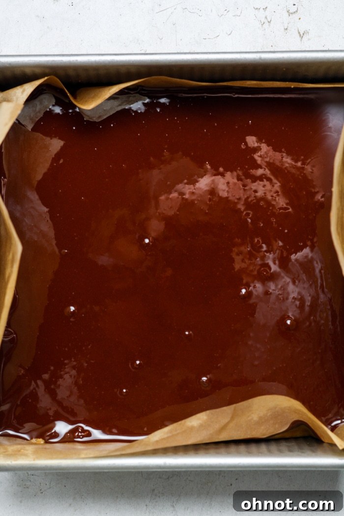 Melted chocolate spread over the caramel layer in a square pan.