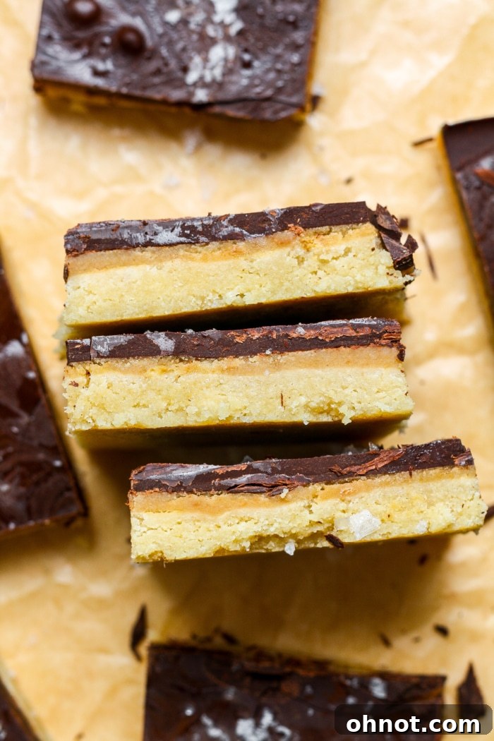 A close-up of a neatly sliced Millionaire Shortbread bar on a white background.