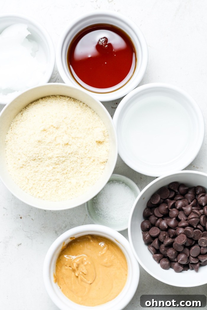 Various ingredients for Millionaire Bars laid out on a surface, including almond flour, maple syrup, peanut butter, and chocolate chips.
