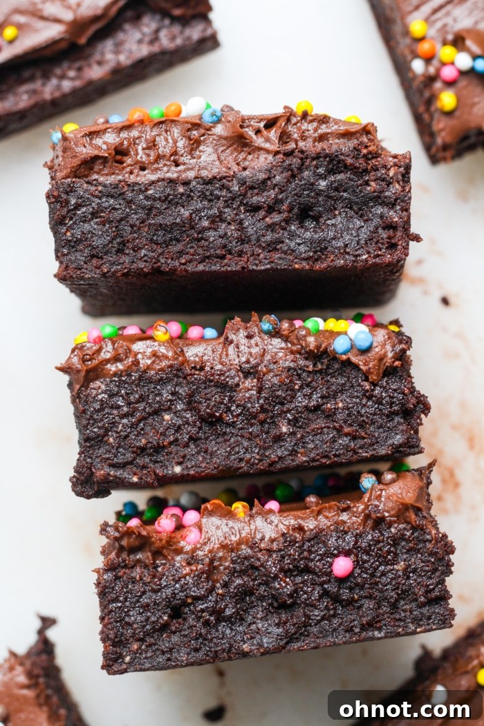 A stack of four fudgy Cosmic Brownies with rich frosting and colorful sprinkles.