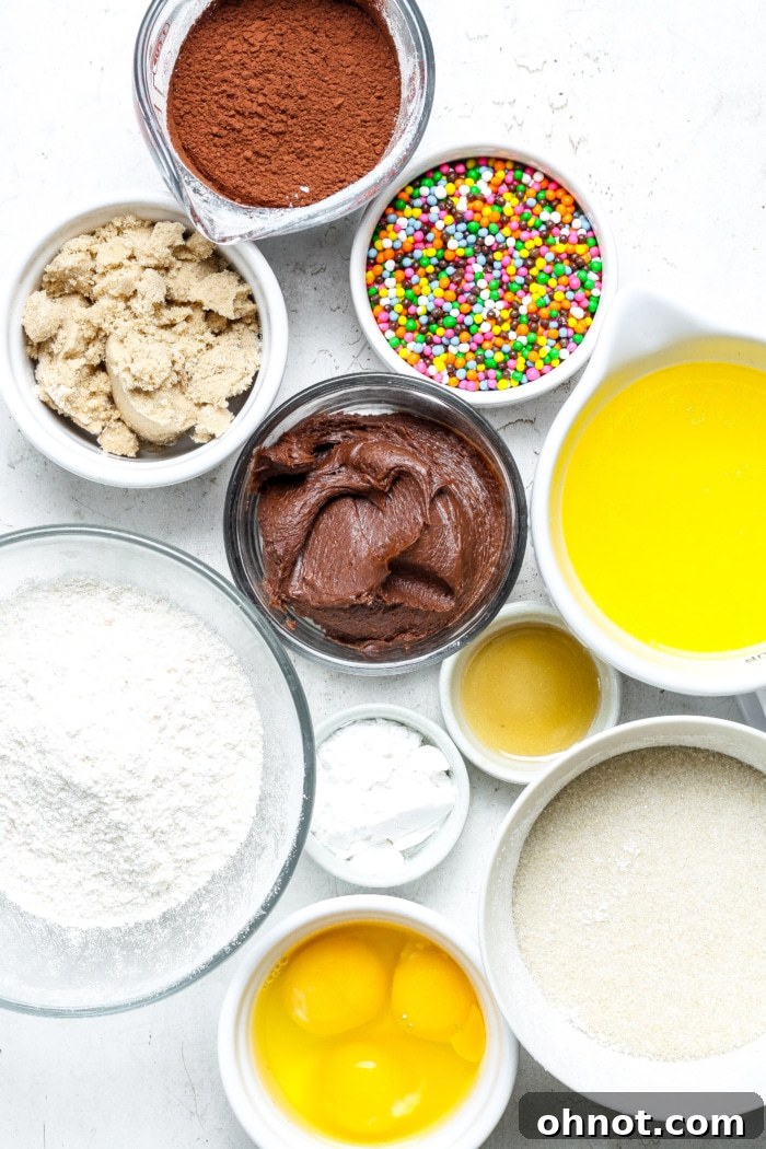 A selection of raw ingredients for making Cosmic Brownies, including sugars, butter, cocoa, eggs, and sprinkles.