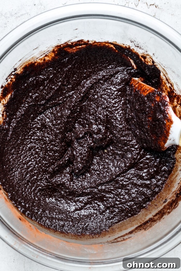 Dark chocolate batter being stirred in a glass bowl.
