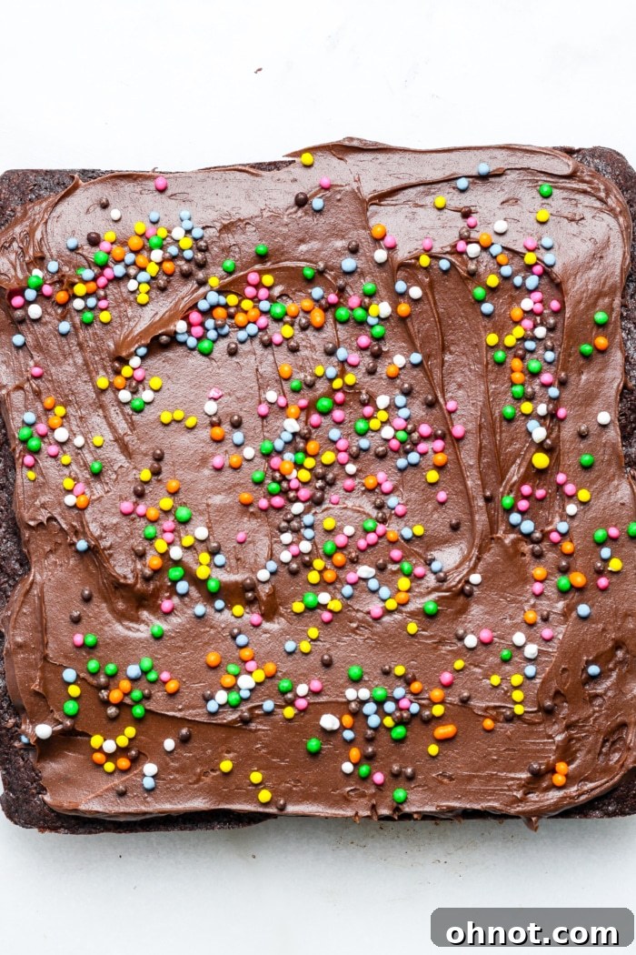 Brownies topped with chocolate frosting and vibrant rainbow sprinkles.