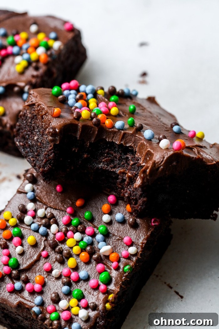 A close-up of a Cosmic Brownie with a bite taken out, revealing its fudgy interior and sprinkled top.