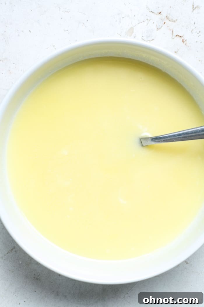 Melted white chocolate and butter mixture in a glass bowl, smooth and creamy.