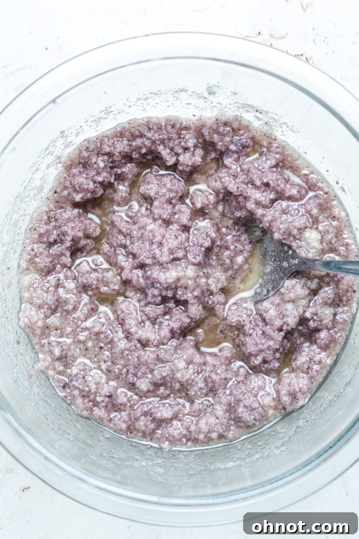 Purple melted mixture with ube extract and eggs, stirred together in a bowl.
