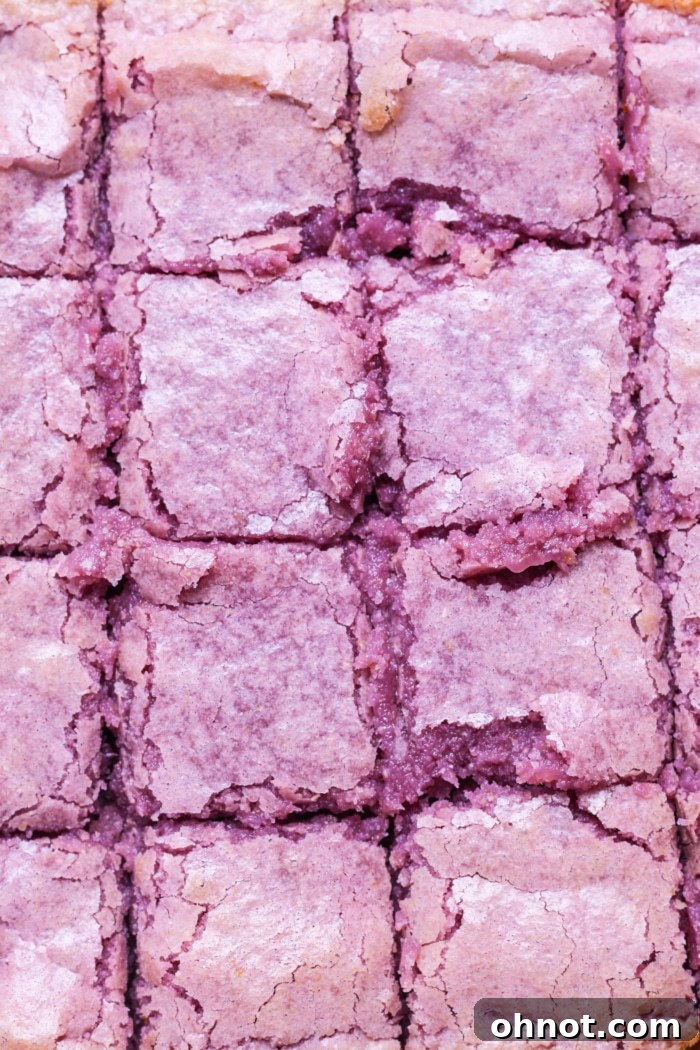 Perfectly sliced white chocolate ube brownies, revealing their fudgy purple interior and a crinkled top.
