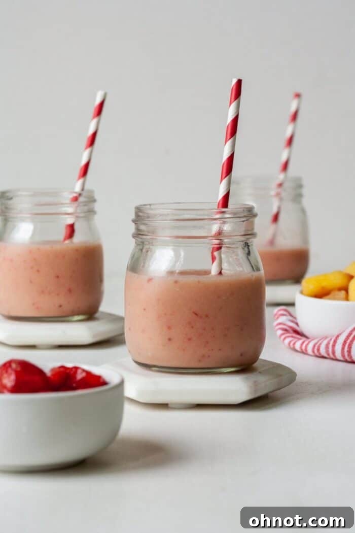 A vibrant AIP smoothie with strawberries and pineapple, garnished with mint.