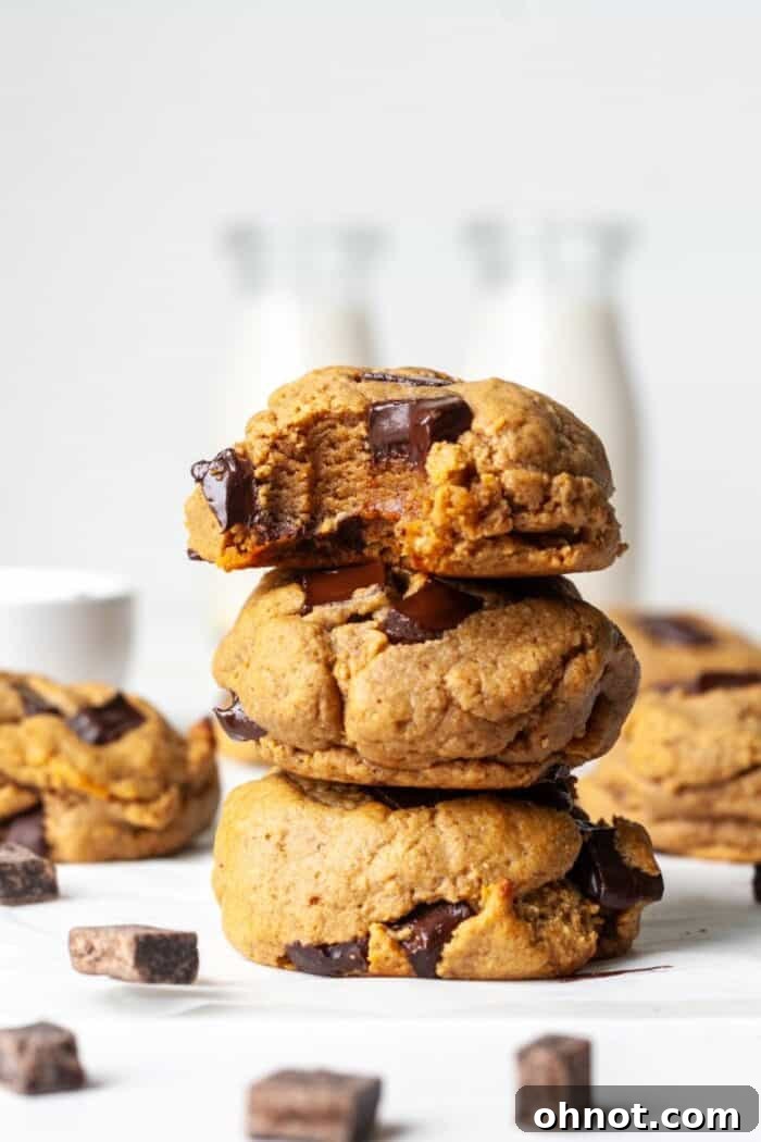 Stack of vegan protein cookies with chocolate chips on a wooden surface.