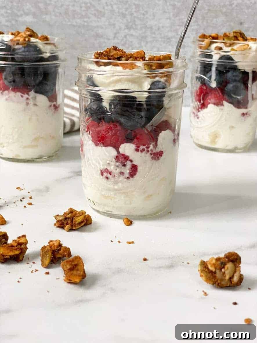 Layers of paleo vegan coconut yogurt parfait with fruit and granola in a glass.
