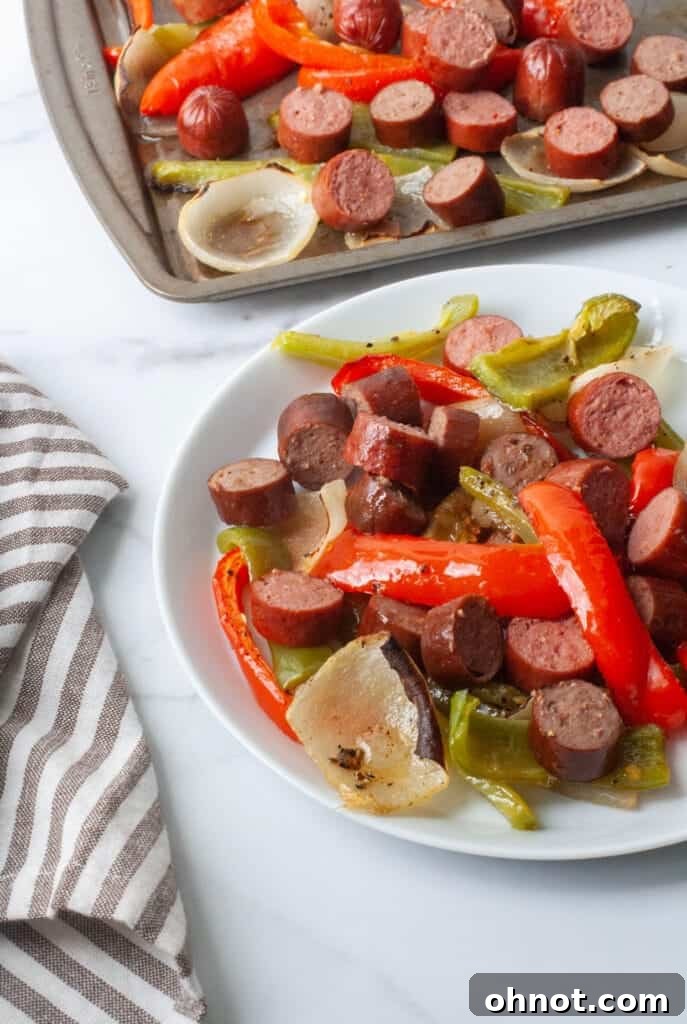 A close-up of a rustic wooden cutting board featuring three perfectly grilled sausages alongside a colorful pile of roasted red peppers, green peppers, and caramelized onions, ready to be served.