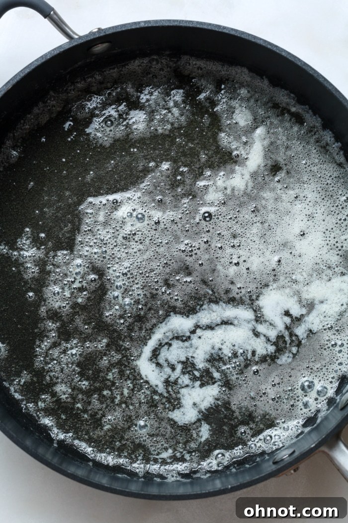 Unsalted butter gently melting in a large skillet on the stovetop