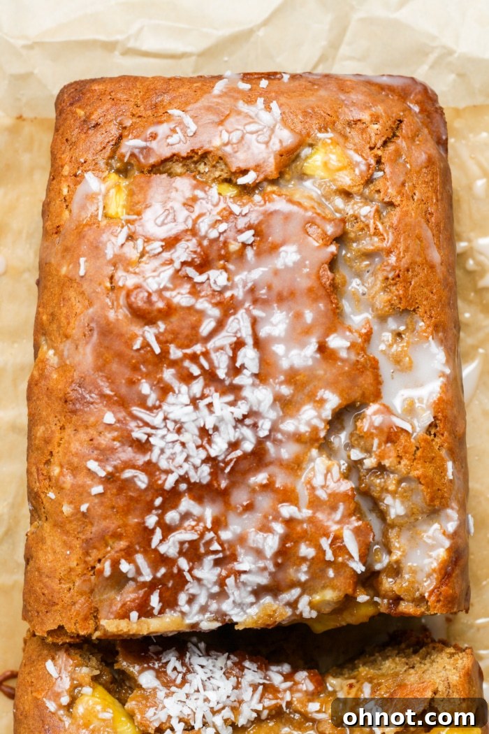 Close-up of a glazed pineapple banana bread loaf with shredded coconut garnish.