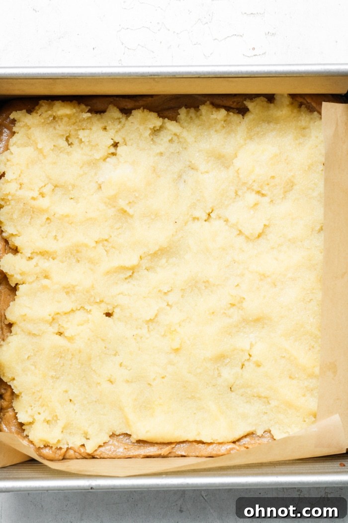 Frangipane almond filling spread over blondie batter in a pan.
