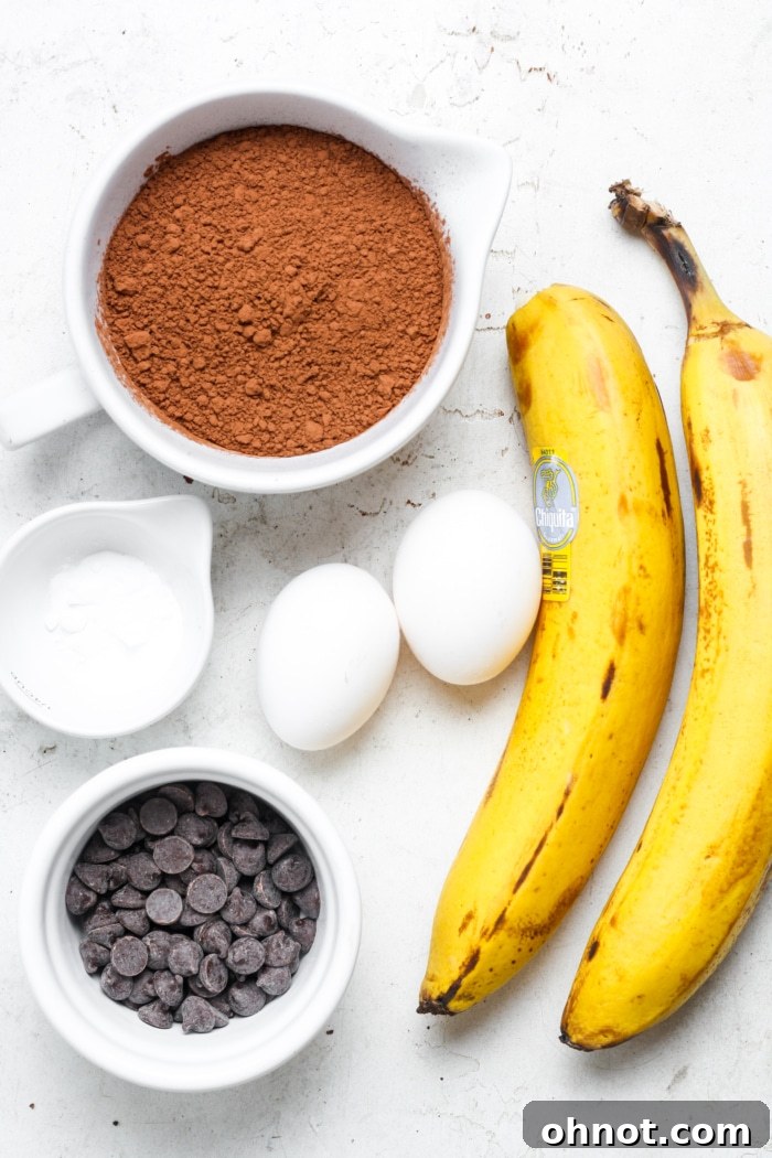 Collection of ingredients for making sugar free brownies, including ripe bananas, eggs, and cocoa powder.
