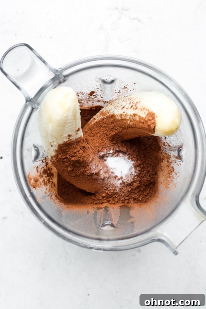Blender with ripe bananas and cocoa powder, ready for blending.