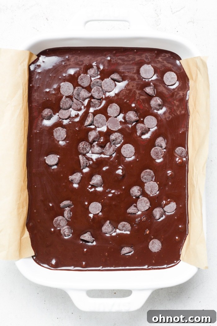 Healthy brownie batter poured into a parchment-lined pan, ready for baking.