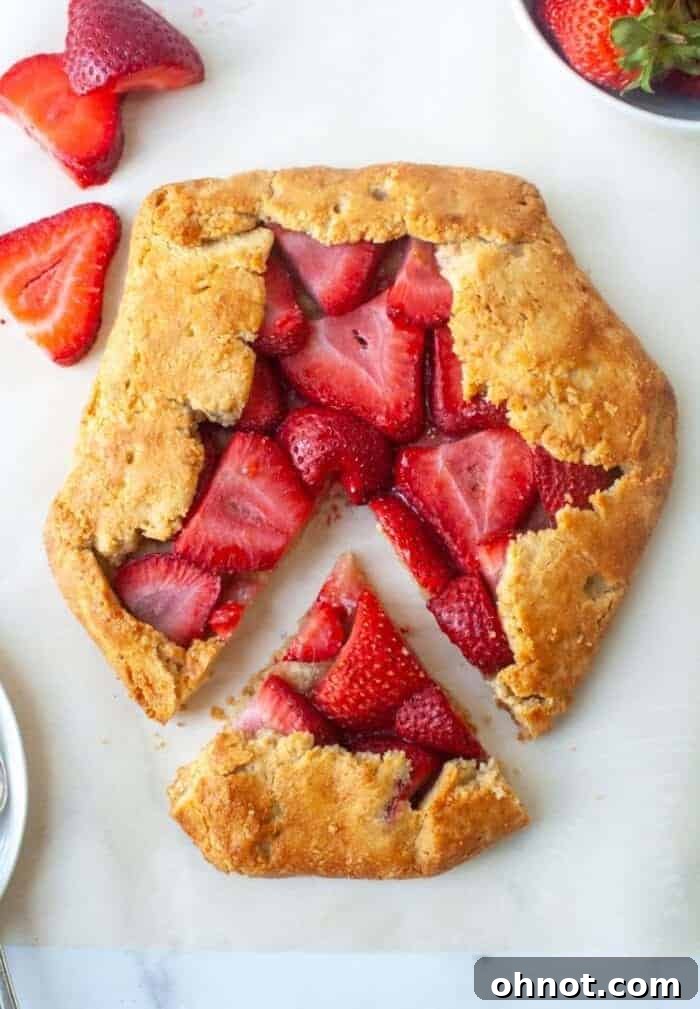 A beautifully rustic gluten-free strawberry galette with golden edges on parchment paper, ready to be served.