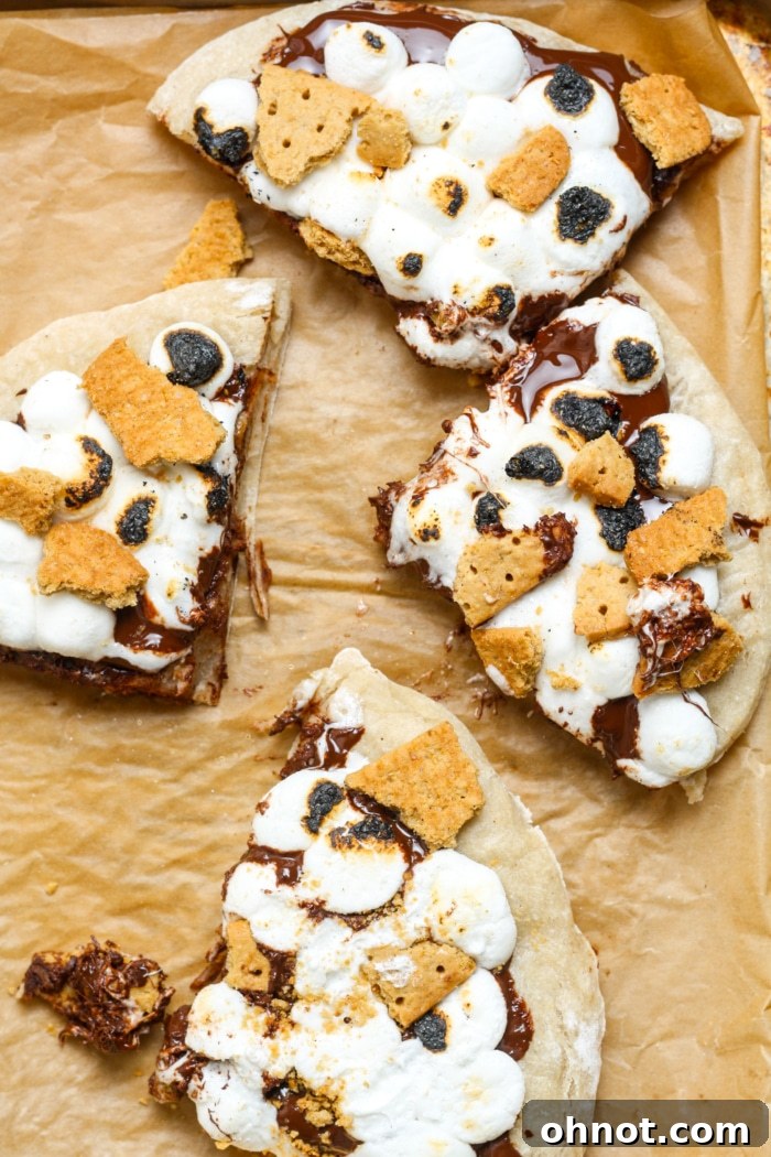 Beautifully cut slices of S'mores Pizza, arranged to highlight the inviting layers of chocolate, marshmallows, and graham crackers.