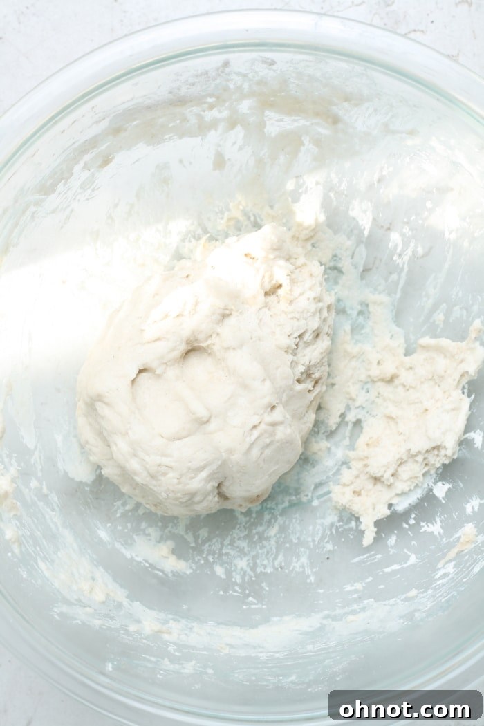A neatly shaped ball of gluten-free pizza dough resting on a surface, ready for pressing.