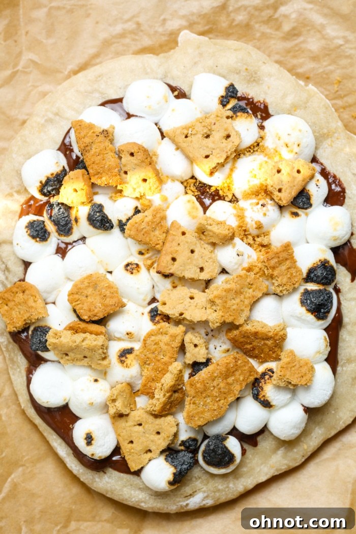 The final S'mores Pizza, adorned with golden-brown marshmallows and a generous topping of crunchy graham cracker crumbs.