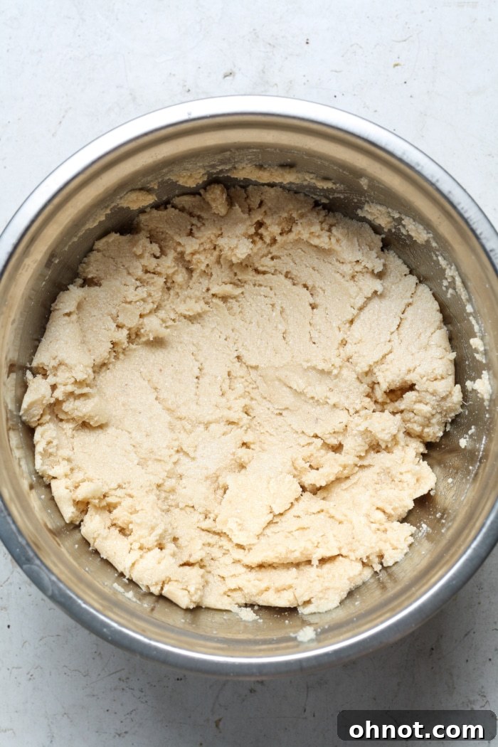 A bowl containing buttery cookie dough for the shortbread crust, ready for the pan.