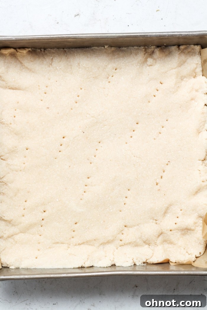 A golden-brown, pre-baked shortbread crust in a square pan.