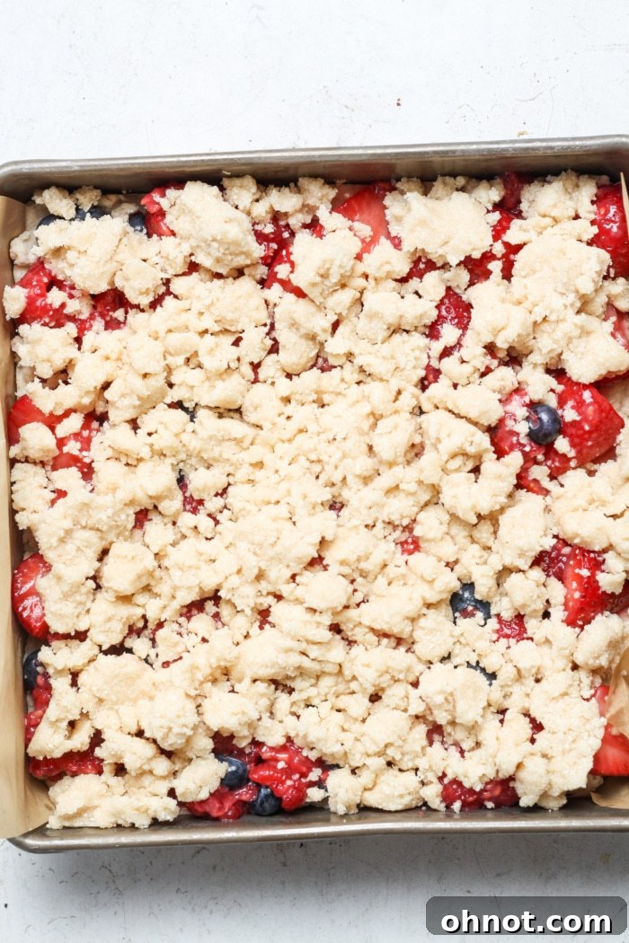 Strawberry filling covered with a generous layer of crumbly topping in a baking pan.